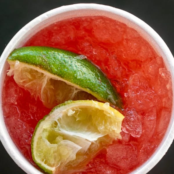 Close-up of a red R-B Drive In cherry limeade with ice and lime wedges.