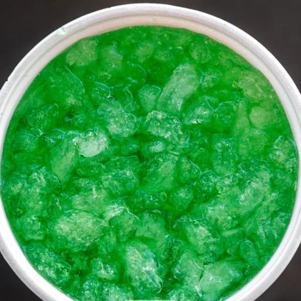 Close-up of a vibrant green soda with ice in a white cup from R-B Drive In.
