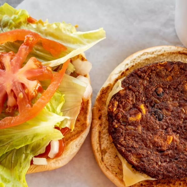 An R-B Drive In burger with a patty, cheese, lettuce, tomato, and onions on a bun.