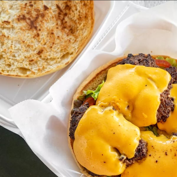 A R-B Drive In burger with melted cheese, lettuce, and tomato, with the top bun removed.