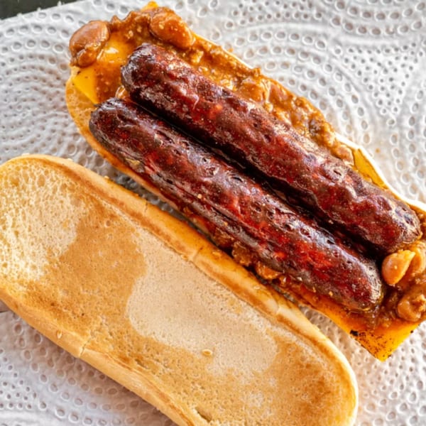 Two R-B Drive In hot dogs with chili and cheese in a bun on a paper towel.
