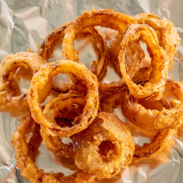 Golden-brown, crispy onion rings from R-B Drive In, served on crinkled aluminum foil.