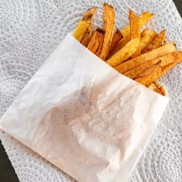 Golden-brown R-B Drive In french fries in a white paper bag, resting on a white paper towel.
